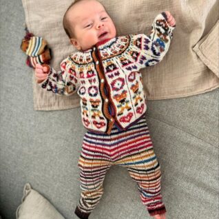 Hentesettet Velkommen til verden. Dette settet har rett-fasong og er designet i Merino 200 bebe og Merino 200 bebe color fra LangYarns. Her vises hele settet på modell i det flerfargede garnet.