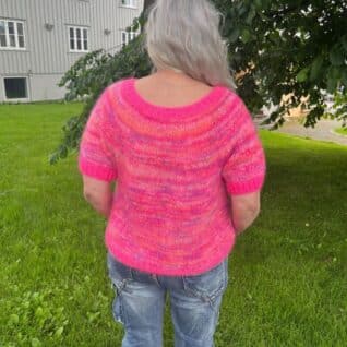 Produktbilde av en modell i den strikkede toppen Vitamin som selges som en strikkepakke og er designet i Bella og Bella Color by Permin. I tillegg til Jawoll fra Langyarns. Her i fargen Pink. bakfra