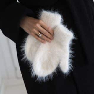 Produktbilde: Modell holder produktet foran seg. Fuzzy Votter designet av Tove Lindtein, strikket i Basta fra Lana Grossa.