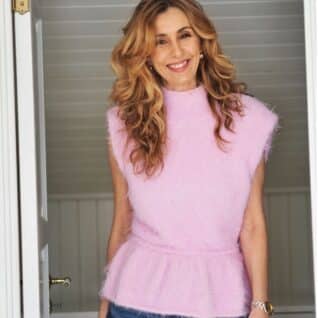 Produktbilde: Modell i front fra hofte til hode hun ser inn i kamera. Strikkepakken Fuzzy Peplum er designet av Tove Lindtein i Basta garn fra Lana Grossa.